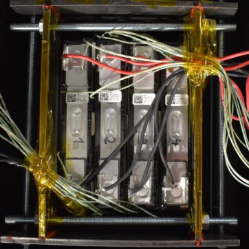 Vier nummerierte prismatische Zellen nebeneinanderliegend mit Verkabelung von oben fotografiert