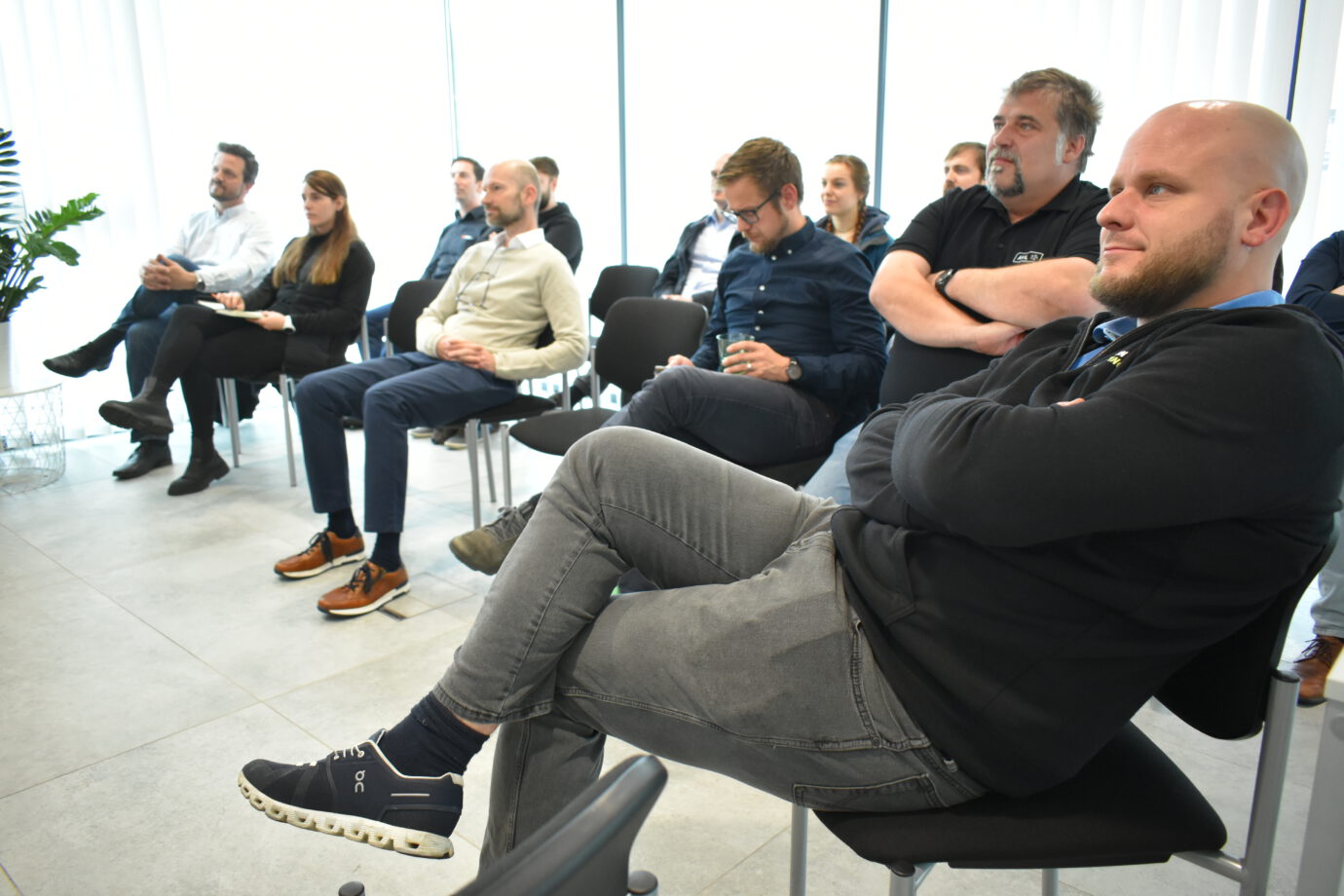 Mehrere Personen im GTL Meeting Raum auf schwarzen Stühlen sitzend, die einem Vortragenden zuhören