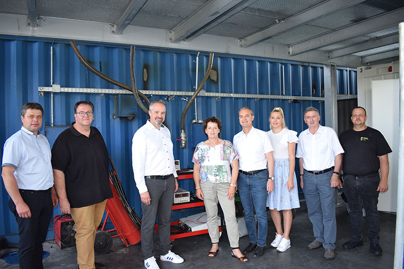 Gruppenfoto von acht Personen vor Container am Testgelände beim Besuch von Landesrätin Mag. Ursula Lackner